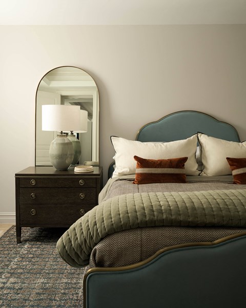 A bedroom with a bed, nightstand, and lamp.