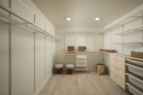 A room with white walls and wooden floors, with shelves and baskets on the floor.