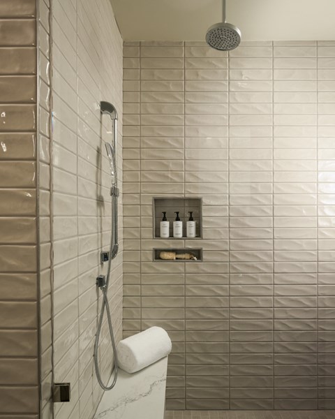 A white toilet paper roll is on a white toilet in a tiled bathroom.