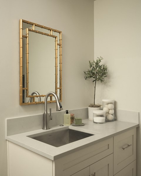 A bathroom sink with a gold framed mirror above it.