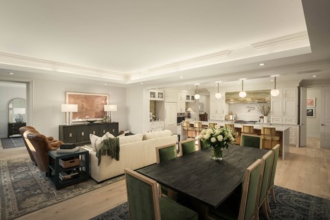 A modern living room with a dark wood dining table and green chairs.