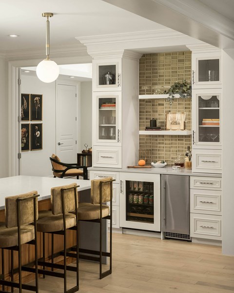 A kitchen with a white and wood theme, featuring a bar area with stools.