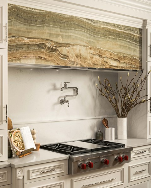 A kitchen with a marble backsplash and a stove top oven.