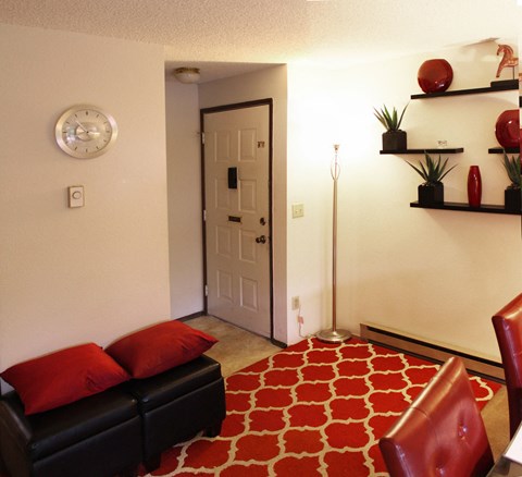 A living room with a black couch and red pillows.