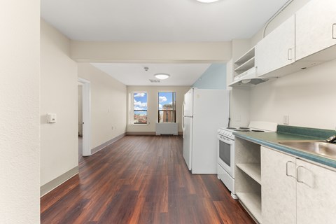 A kitchen with white cabinets and a wooden floor.