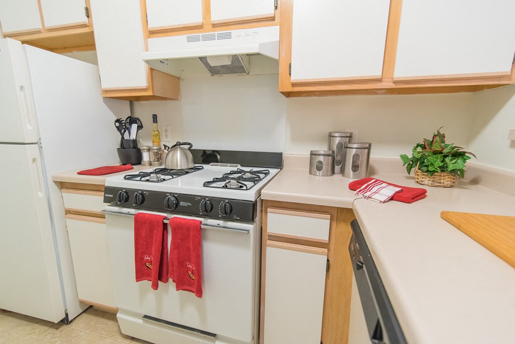 a kitchen with white appliances and wooden cabinets and a stove top oven
