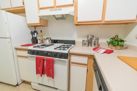 a kitchen with white appliances and wooden cabinets and a stove top oven