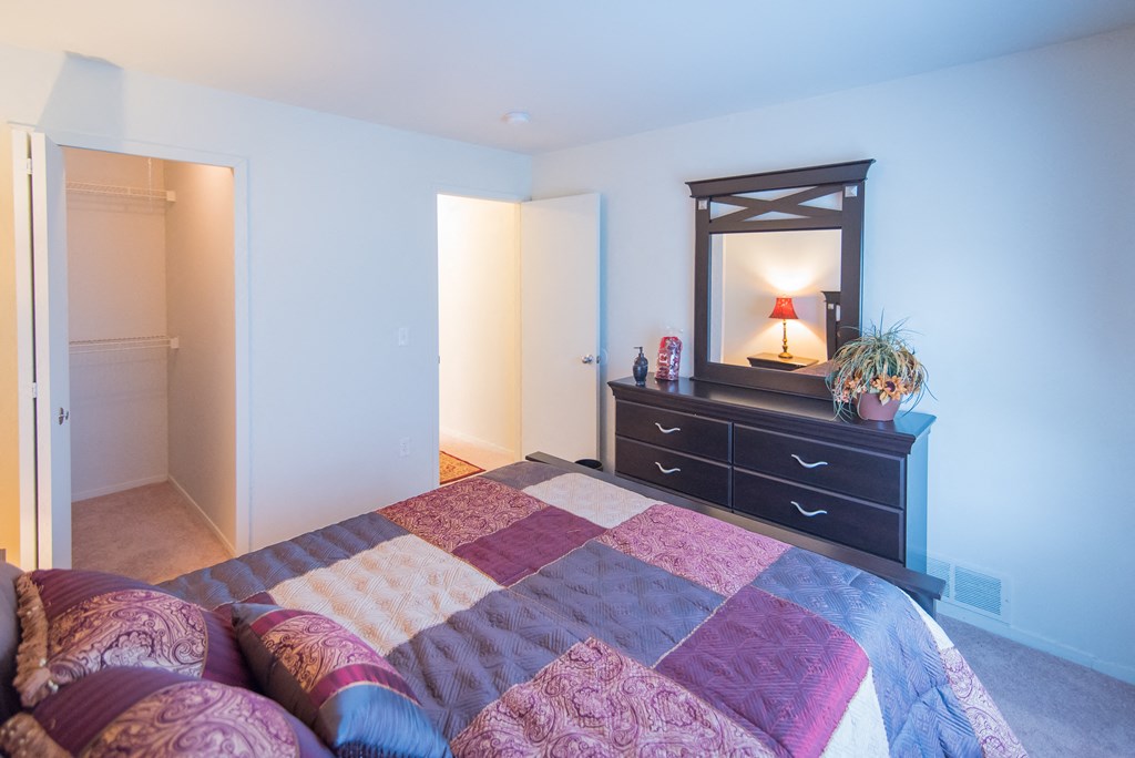 a bedroom with a bed and a dresser with a mirror