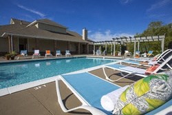 a swimming pool with chairs and a building in the background