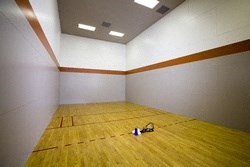 a large room with a wooden floor and a racquetball court