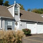 a white house with two garage doors and a roof