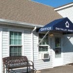 a white building with a blue awning and a bench in front of it