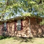 a red brick house with a tree in front of it