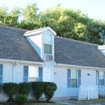 a white house with blue doors and a gray roof