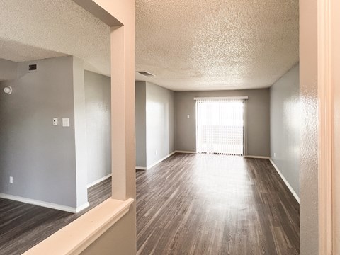 an empty living room with wood floors and a large window in Dallas, TX, 75216