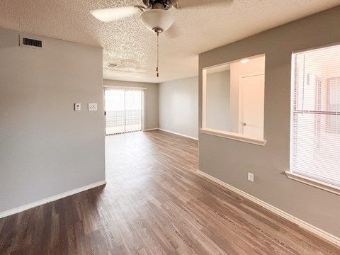 an empty living room and dining room with wood flooring and a window in Dallas, TX, 75216