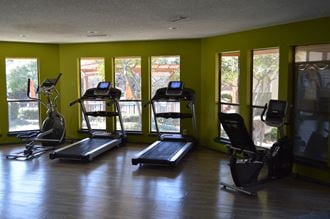 a workout room with treadmills and windows in a building