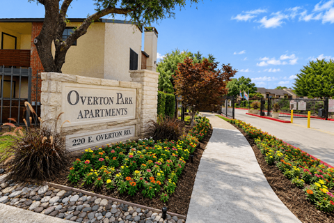 The image shows a beautifully landscaped entrance to Overton Park Apartments.
