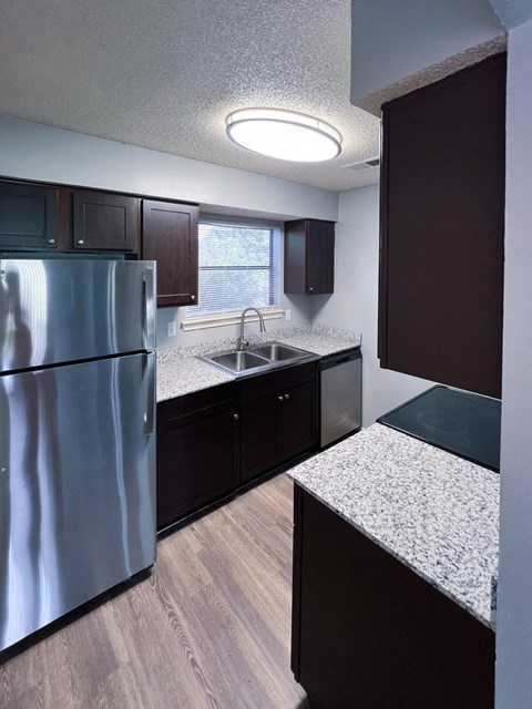 an empty kitchen with granite counter tops and stainless steel refrigerator in Dallas, TX, 75216