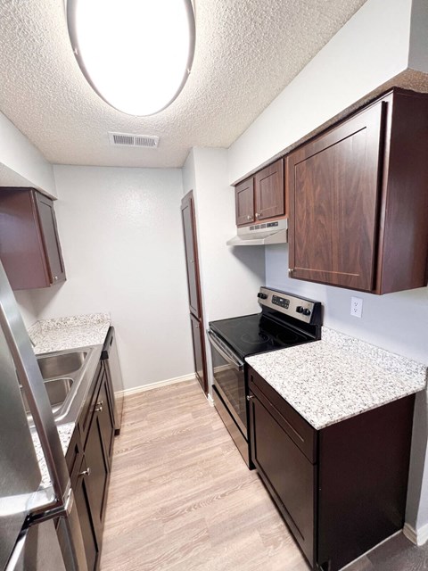 a kitchen with granite countertops and stainless steel appliances and wooden cabinets in Dallas, TX, 75216