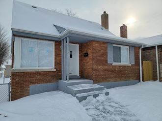 the front of a brick house in the snow