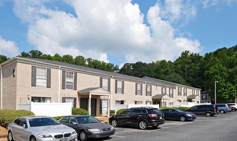 A row of cars parked in front of apartment buildings.
