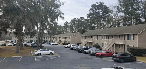 A parking lot with cars and apartment buildings in the background.