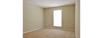 A room with a carpeted floor and a window letting in light.