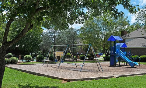 A playground with a swing set and a blue slide.