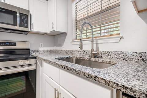 A kitchen with a granite countertop and a stainless steel sink.