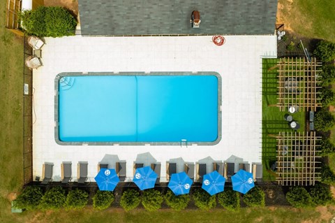 A large swimming pool surrounded by blue umbrellas and a white building.