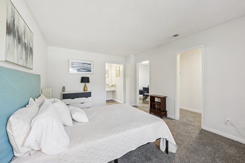 A bedroom with a large bed and a painting on the wall.