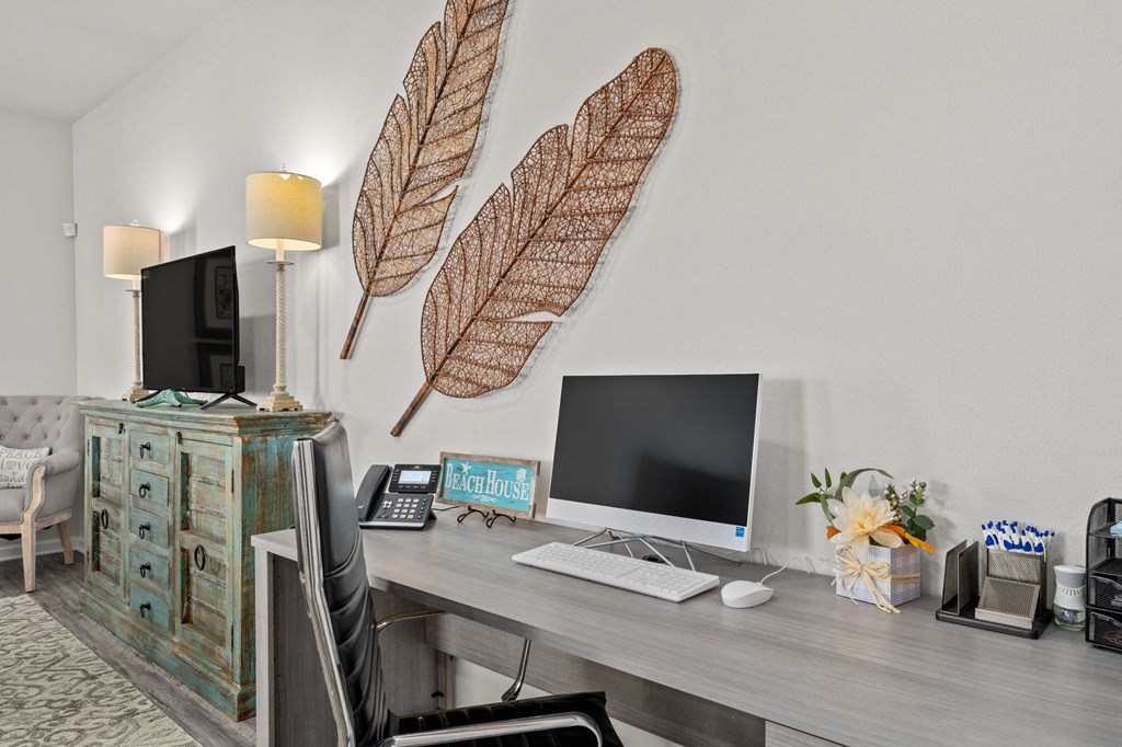 a home office with a computer and leaves on the wall