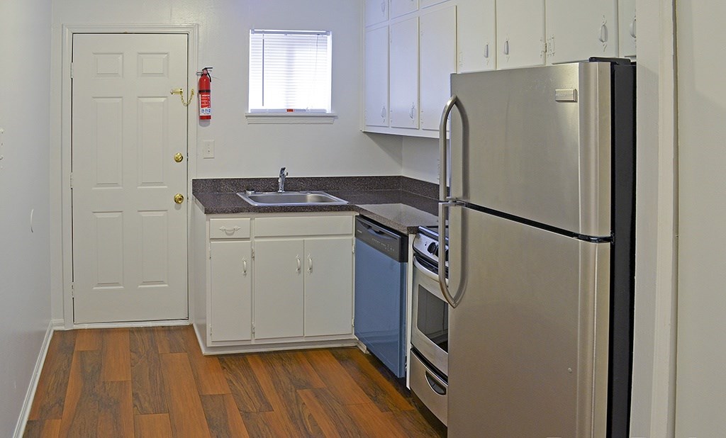 A kitchen with a stainless steel refrigerator, sink, and cabinets.