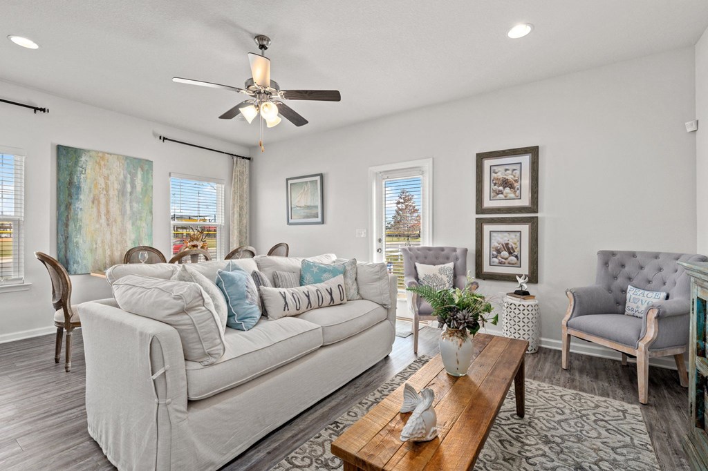 a living room with couches and chairs and a ceiling fan
