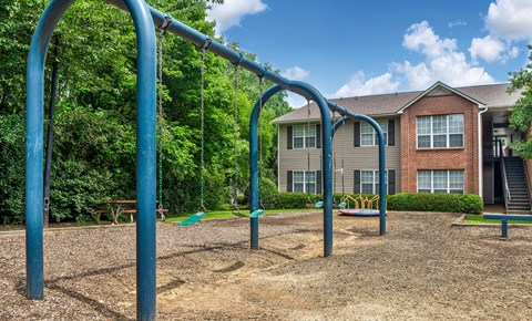 A playground with a swing set in front of a residential building.