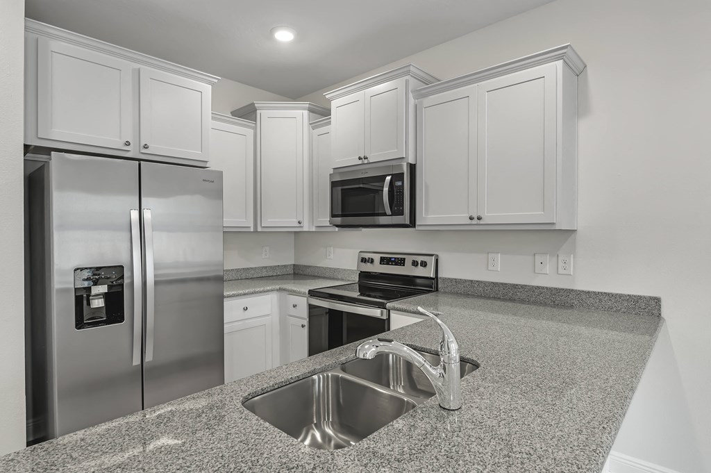 a kitchen with white cabinets and granite countertops