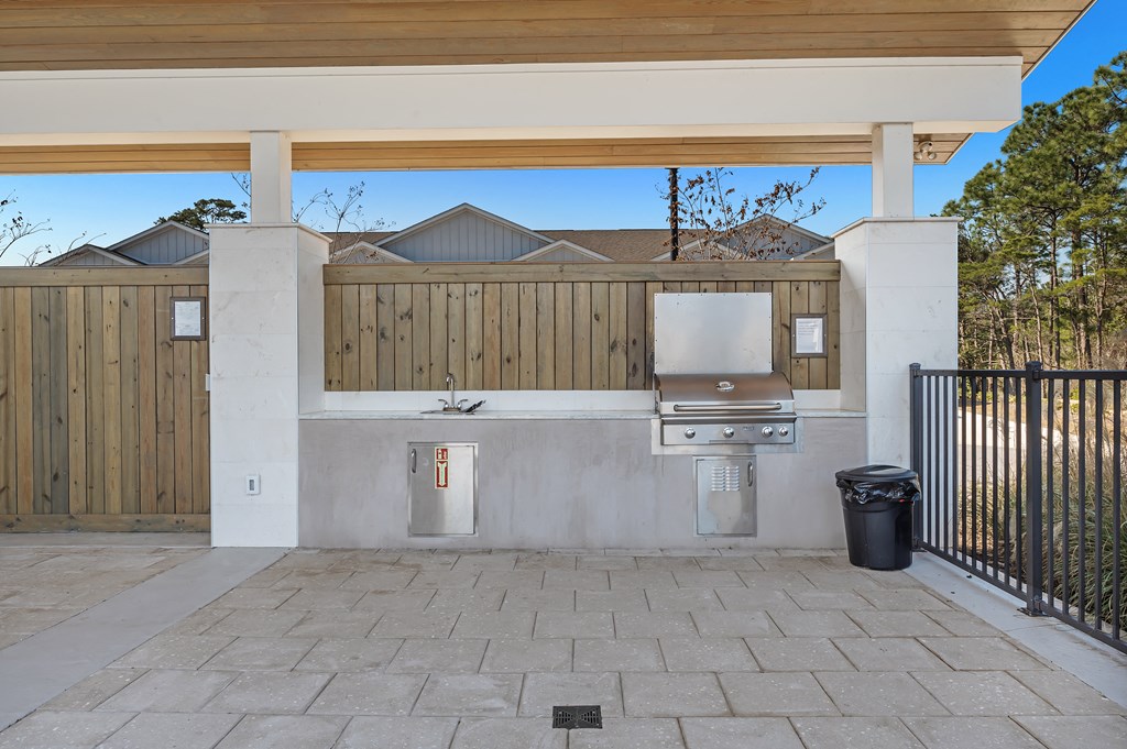 an outdoor kitchen with a grill and a trash can