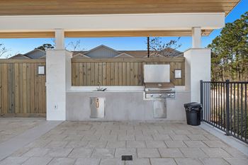 an outdoor kitchen with a grill and a trash can
