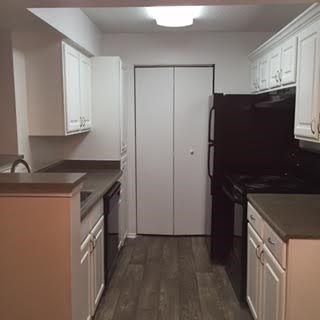 A kitchen with white cabinets and a black fridge.
