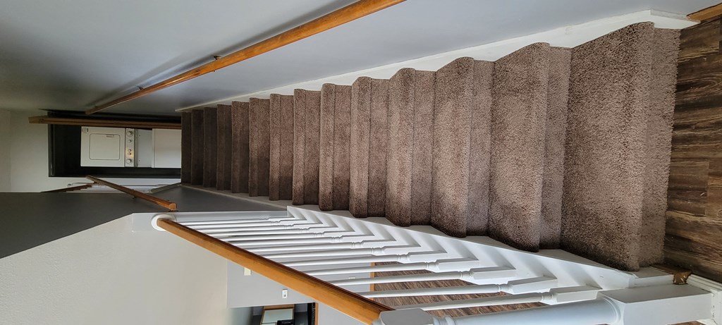 a view from the top of the stairs looking down into the living room