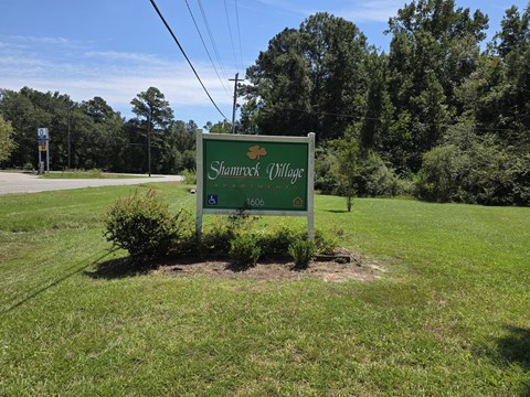 A green sign that says Shamrock Village on it.