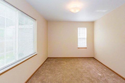 an empty room with two windows and a carpeted floor