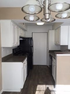 A kitchen with white cabinets and a black refrigerator.