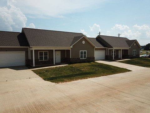A row of houses with brown roofs and white garage doors.
