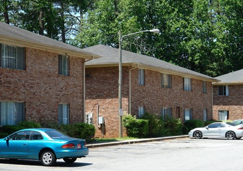 A blue car is parked in front of a brick building.