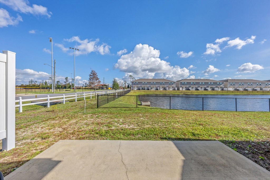 a view of a park with a fence and a body of water