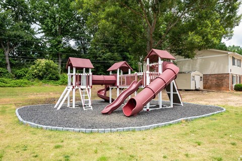 A red slide in a playground with a white frame.