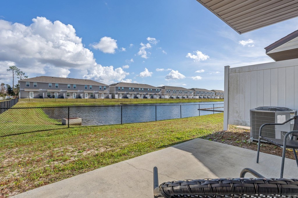 a patio with a grill and a lake with apartments in the background