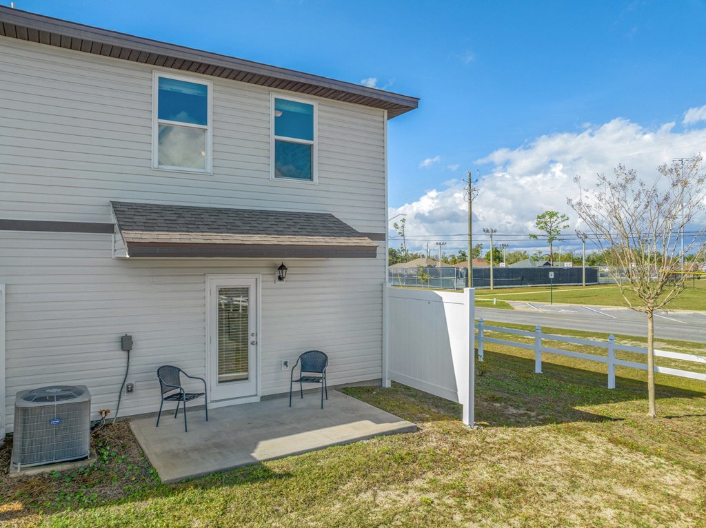a white house with a patio and two chairs in front of it